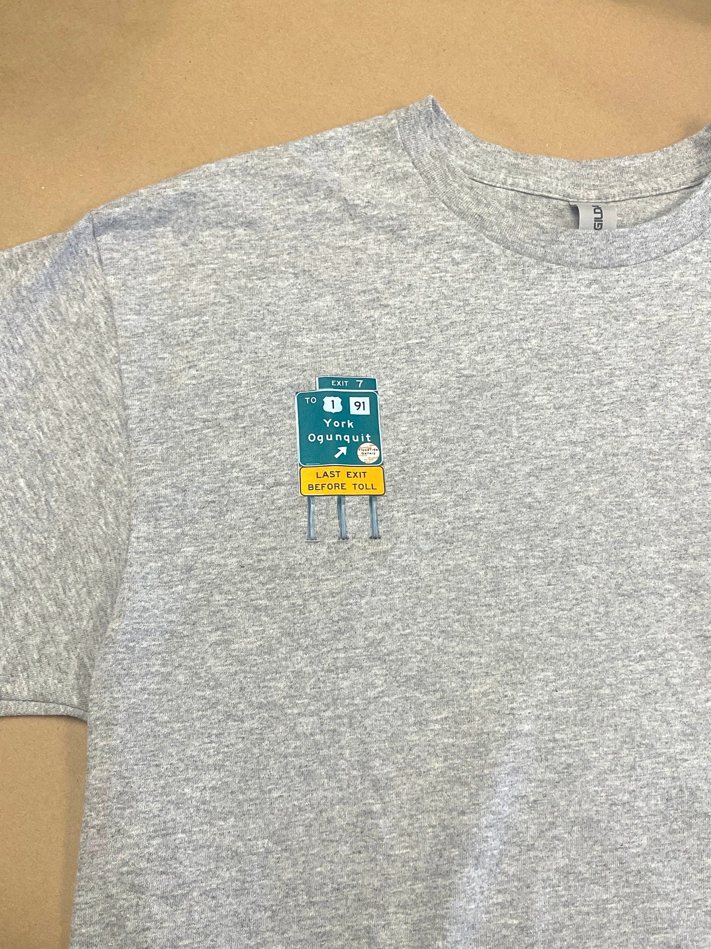 Gray t-shirt with a small patch on the chest against a brown background